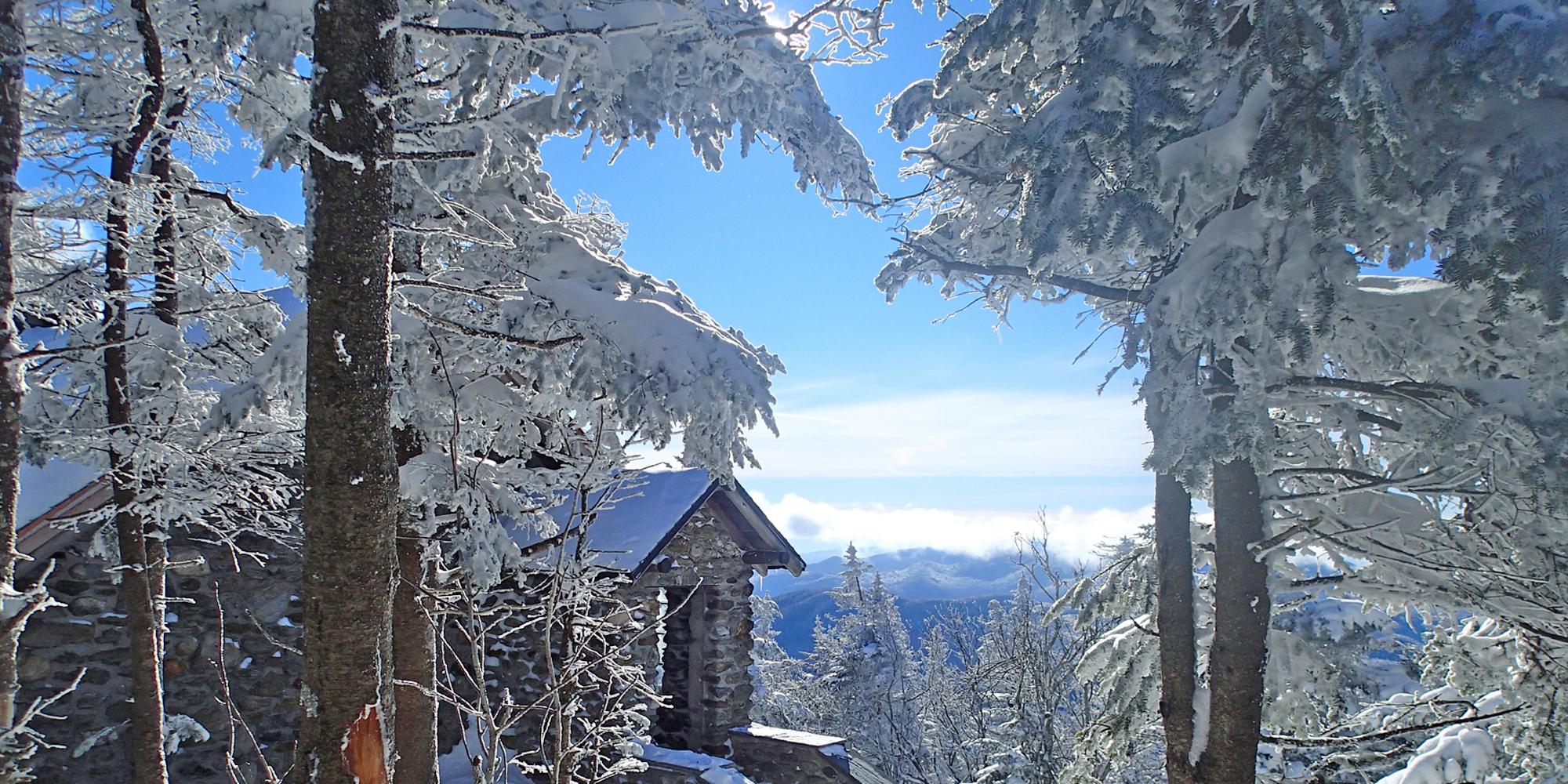 A bluebird day at the Stone Hut on Mount Mansfield with a coating of snow on trees and buildings.