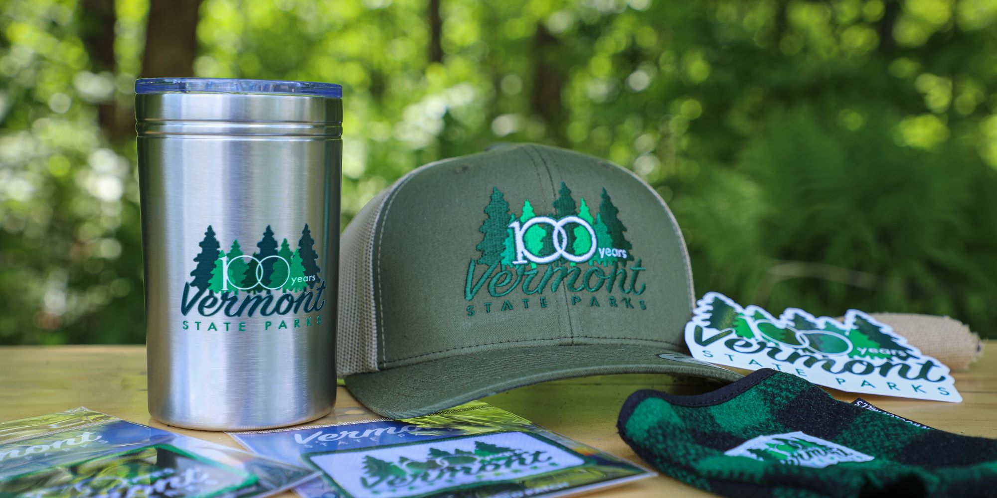 A hat, mug, sticker, and patchs with the 100th anniversary state parks logo